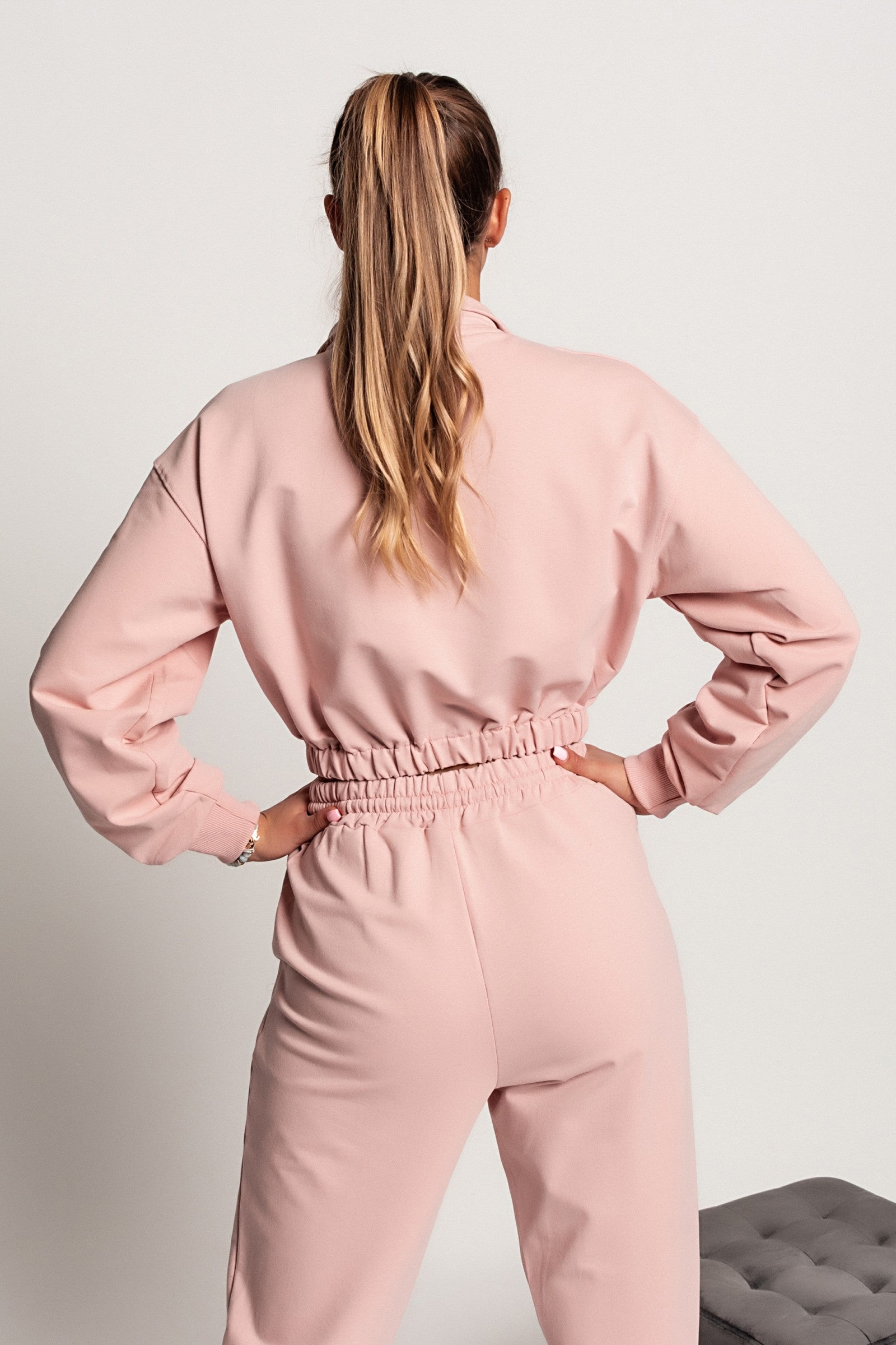 Svetlo roza skrajšana športna majica Polistena z dolgimi rokavi in visokim ovratnikom z zadrgo.